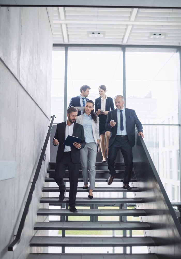 Confident businesspeople standing on staircase in office